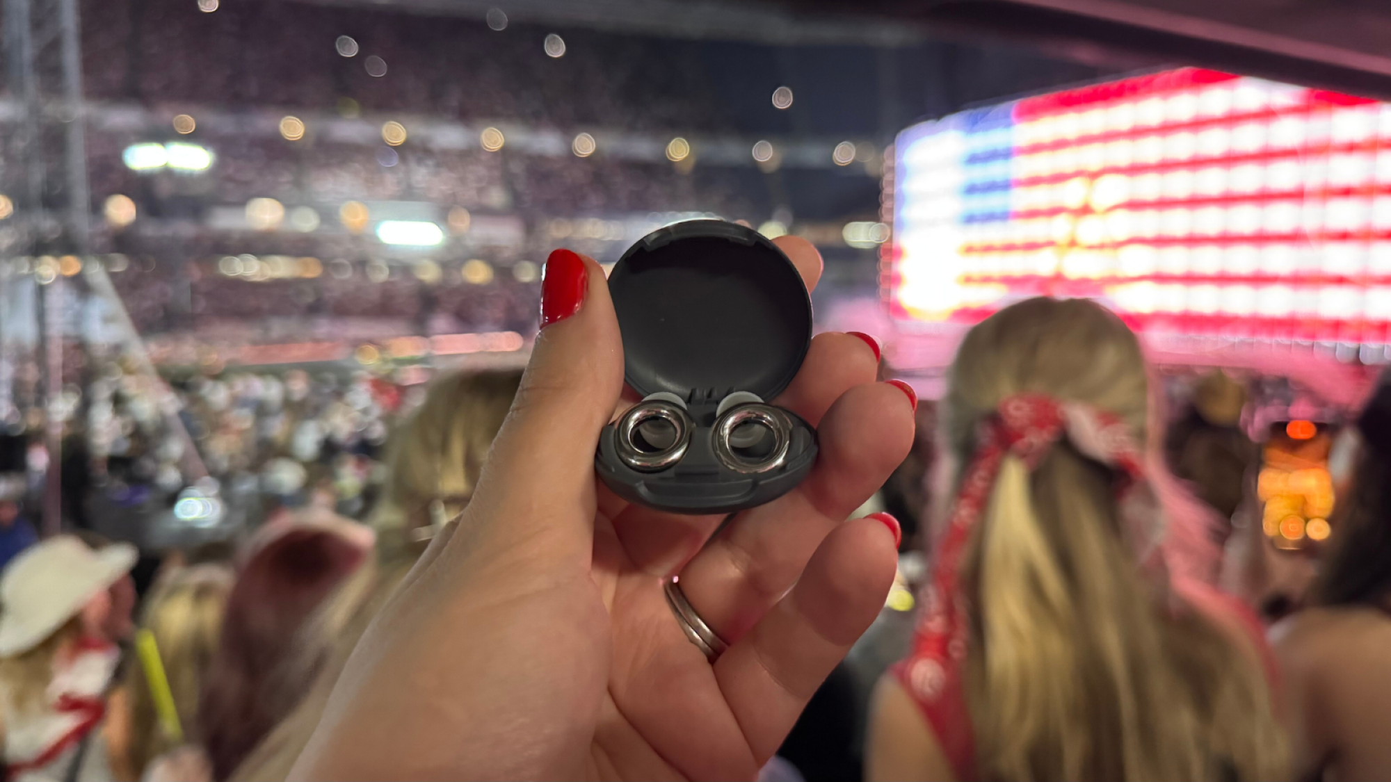 a close-up of the author's hand holding a pair of loops experience 2 in their case at the cowboy carter tour