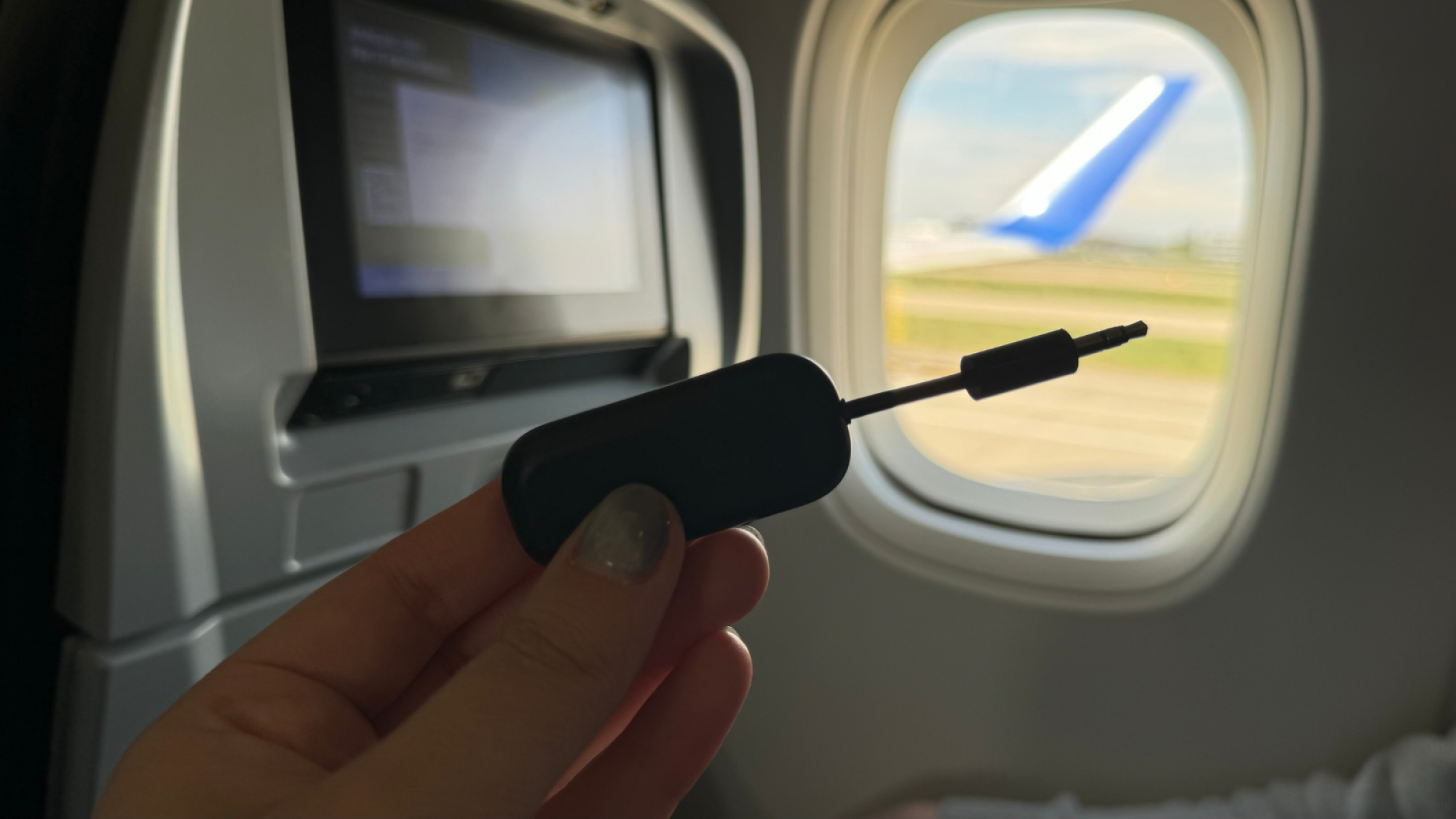 a close-up of an airfly pro held in front of an airplane window