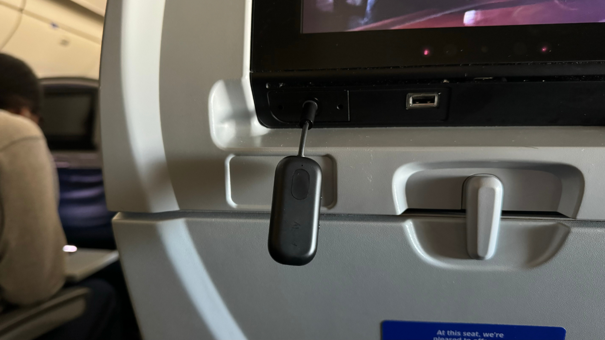 a close-up of an airfly pro plugged into the seatback screen of an airplane
