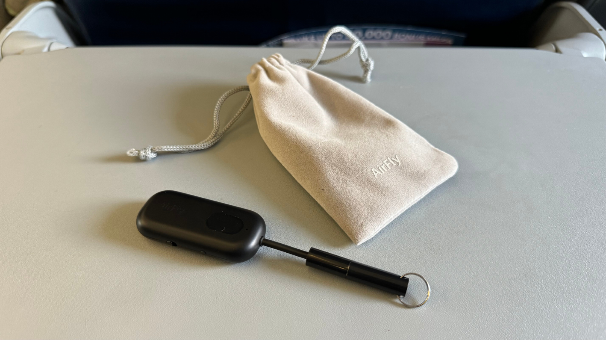 an airfly pro with its travel pouch on an airplane's tray table