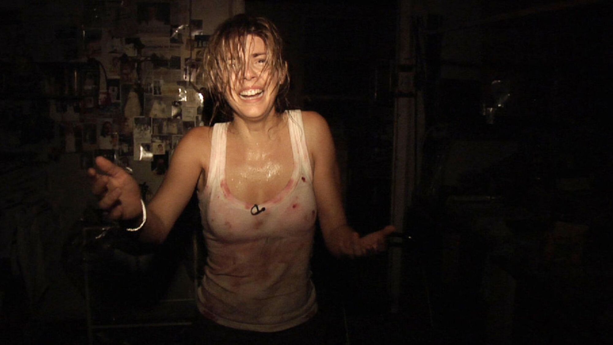 A female reporter splattered with blood cries in a dark room.