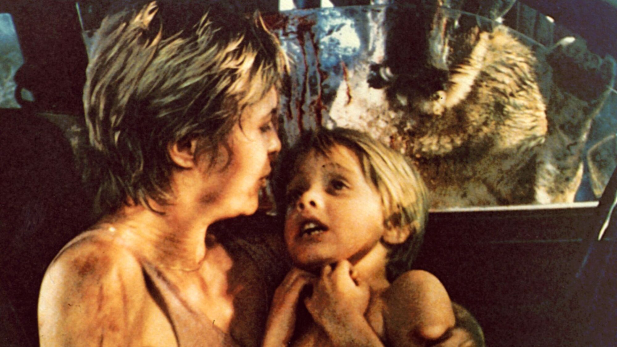 Dee Wallace and Danny Pintauro cower in a car as Cujo looks on.